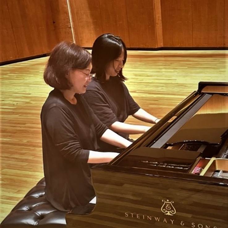 A group of women playing a piano  Description automatically generated with low confidence